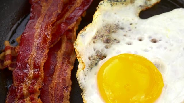 Bacon with fried Eggs (rotating on a wooden plate; seamless loopable; 4K)