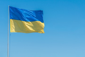 Yellow-blue flag of Ukraine in the wind against the blue sky.