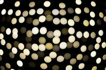 Big bokeh circles in yellow and white on dark black background for holiday / Christmas concept