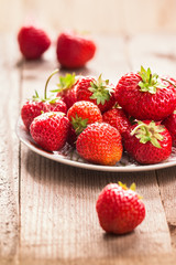 Ripe strawberries on a white plate,  on wooden table