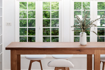 Wooden table and chairs in white room, pot plant, with windows and garden outside for concept of home office, work from home, desk in living room / home desk.