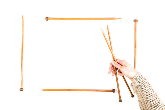 Knitting background. Woman hand and wooden knitting needles on white background