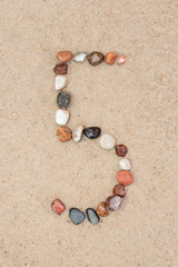 Fototapeta na wymiar pebble 5 number on sand selective focus