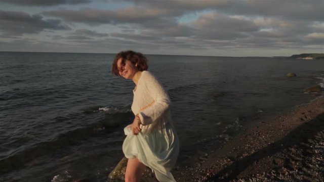 Red-haired girl is walking along the seashore.