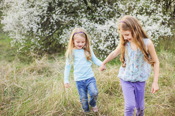 Fototapeta premium Sisters walk in the garden of flowering trees