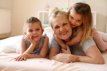 Grandmother playing in bed with her granddaughters.