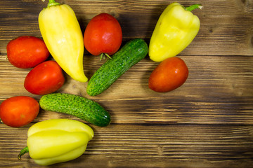 Tomatoes, cucumbers and peppers on wooden background
