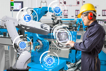 Engineer using laptop computer for maintenance automatic robotic hand machine tool at industrial...