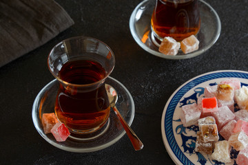 Delicious Turkish delight with tea on a black background. Turkish lukum.