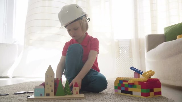 Boy imitating engineer constructing a building with toy blocks