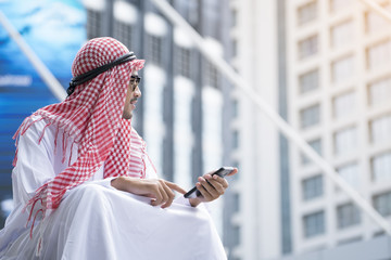 Arab businessman working with his phone on building background