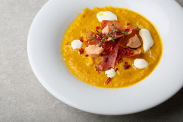 Hot pumpkin soup in white bowl