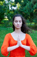 Girl an orange dress is meditating in the park