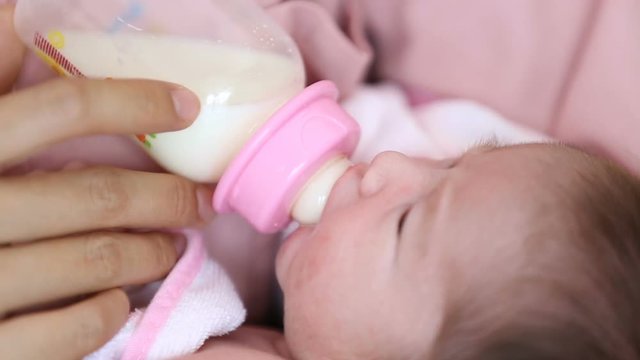 Young mother holding and feeding her baby by bottle of milk.