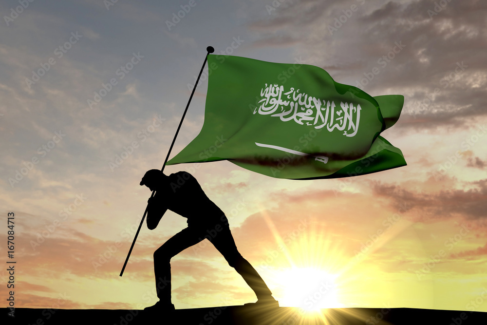 Wall mural saudi arabia flag being pushed into the ground by a male silhouette. 3d rendering - Wall murals