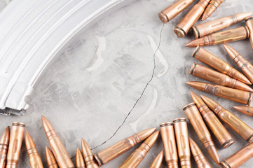 Silver metal full magazine for assault rifle and many scattered bullets on old grey broken concrete