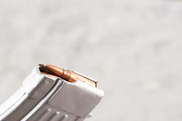 Silver metal full magazine for assault rifle on grey concrete