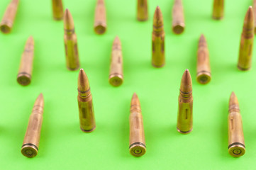 Row of many metal bullets for assault rifle on green background