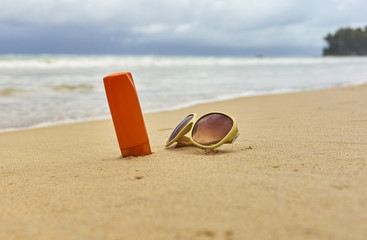 Fototapeta na wymiar Sunscreen cream, sunglasses on sea coast.