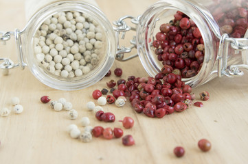 Piper nigrum fruit, white pepper and Schinus molle, American false pink pepper, spilled on the wooden table