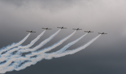 Aerobatic aircraft display team trail of smoke cloudy sky