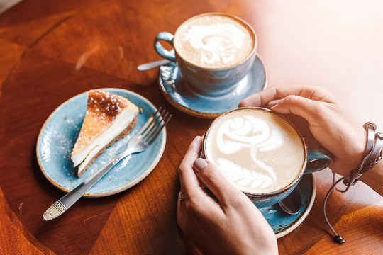 Two cappuccino cups with cheese cake on the brown wooden table in cafe, modern breakfast and resting time concept in restaurant