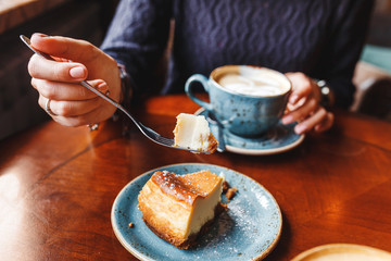 Woman eating cheesecakes with spoon in cafe