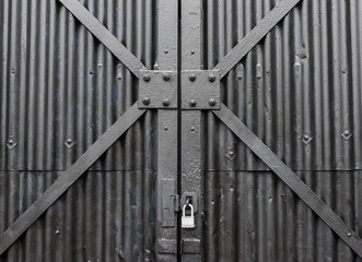 Padlocked and closed matte black metal security gate detail