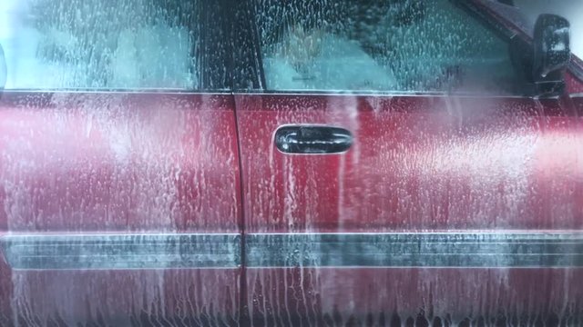 Time lapse of a woman in a vehicle during a car wash process in a automatic tunnel car wash. 