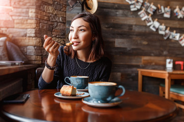 beautiful young asian woman sitting in a cafe and eating delicious cake