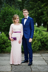 Good-looking couple celebrating their graduation from the university, posing outside in beautiful clothing.