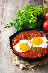 Mexican breakfast: Huevos rancheros in iron frying pan on wooden table