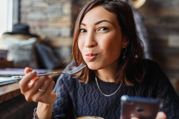 beautiful young asian woman sitting in a cafe and eating delicious cake
