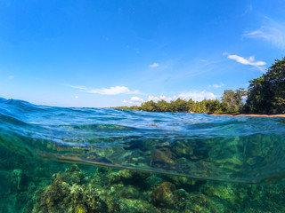 Double landscape with sea and sky. Sea panorama split photo. Undersea view with tropical island seashore.