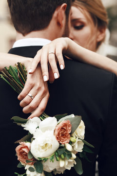 Bride crosses her tender hands on groom's back