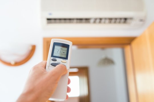 Hand adjusting temperature of home air conditioner