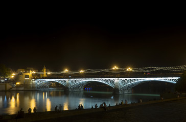Iluminación nocturna del hermoso puente de Triana en la ciudad de Sevilla, España