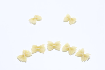 A sad smiley, laid out of pasta on a white surface.