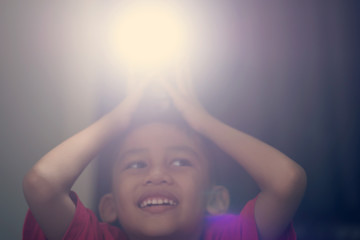 A boy holding a camera flash on his head and smiles happily.