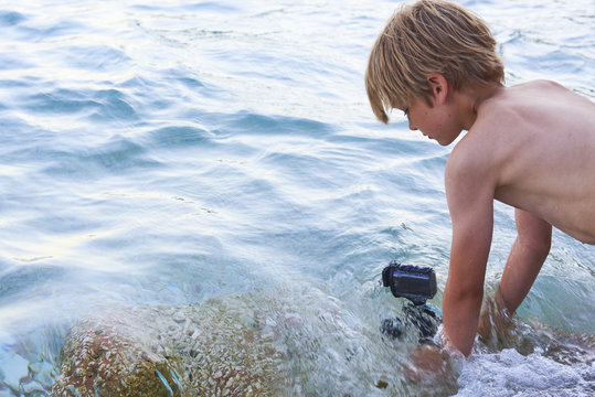Child boy shooting movie with action outdoor waterproof camera in the sea