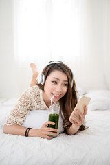 Woman Relaxing in bed and listening to music, relaxing in her living room