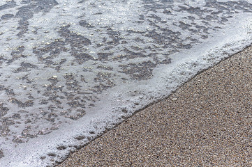 Wave with foam on a sandy beach