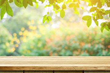 Empty wooden table over blurred tree with bokeh background, for product display montage