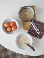 Breakfast with oatmeal and eggs. White table