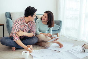 Attractive young asian adult couple looking at house plans.