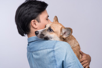 A man snuggling and hugging his dog, close friendship loving in studio background
