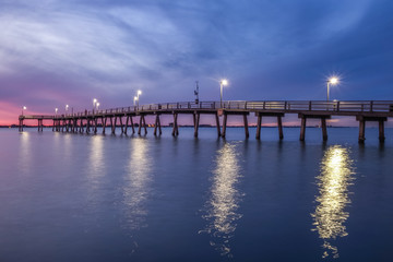 Fototapeta na wymiar Fishing pier at dusk with dramatic sky