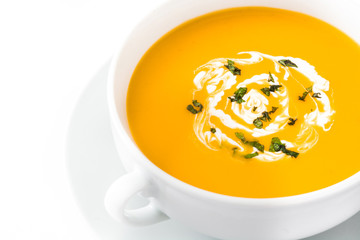 Pumpkin soup in white bowl on wooden table
