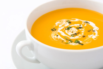 Pumpkin soup in white bowl on wooden table
