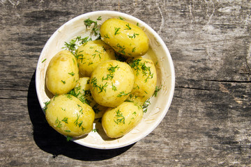 Naklejka na ściany i meble Boiled new potatoes with butter and dill on old wooden table. Top view